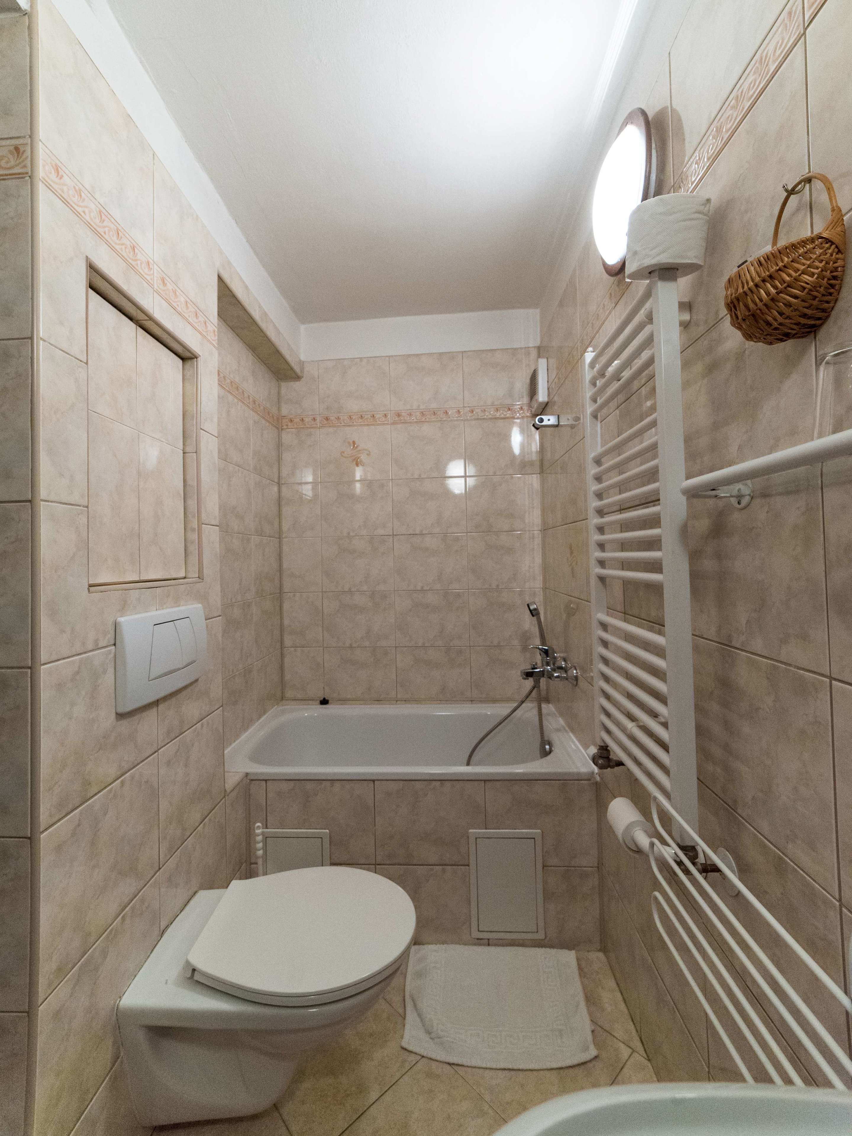 A bathroom with a bathtub, toilet, and a towel rack.