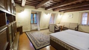Un dormitorio con una cama grande, un sofá, una mesita y una ventana con cortinas.