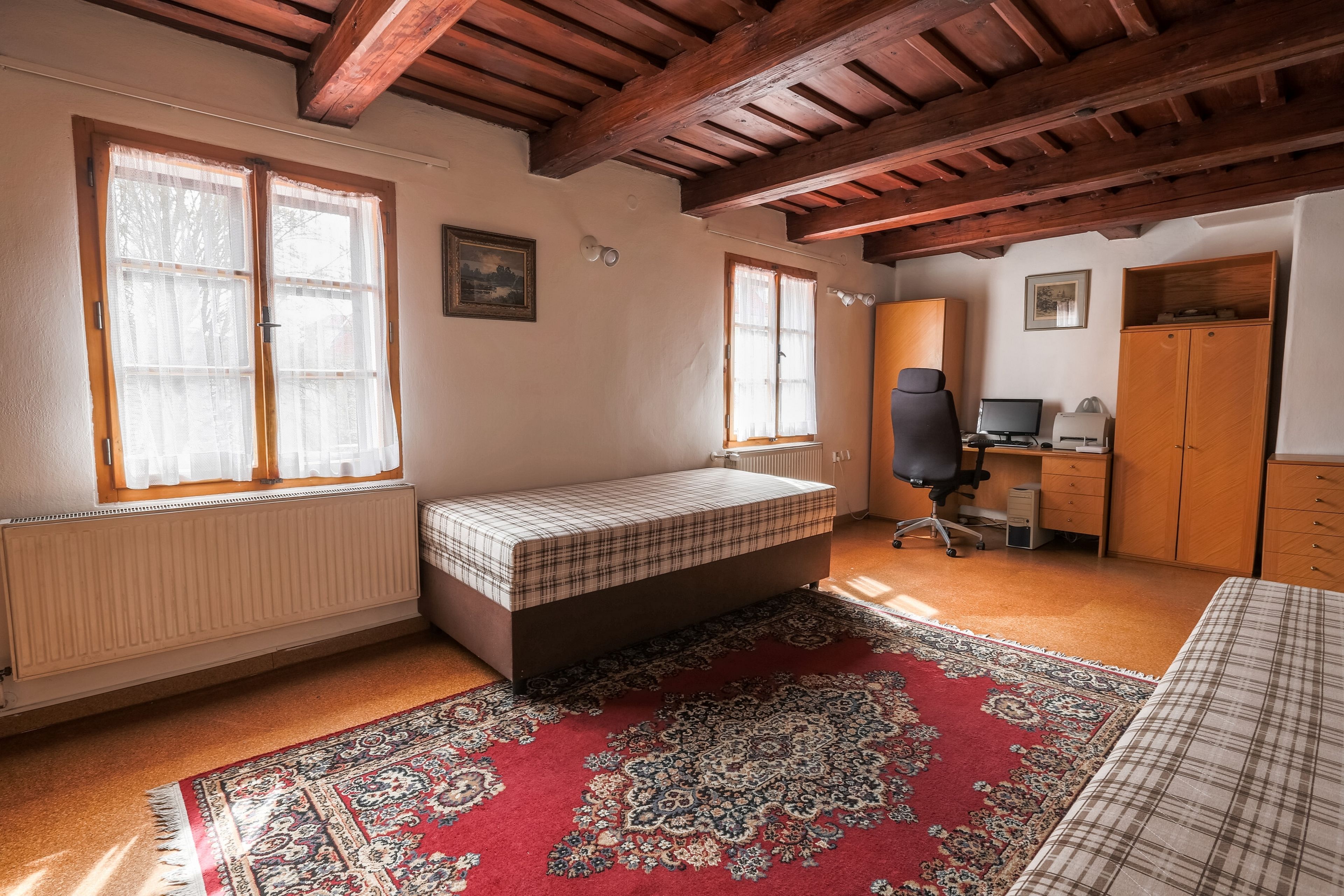 Un dormitorio con una cama, un escritorio y una computadora.
