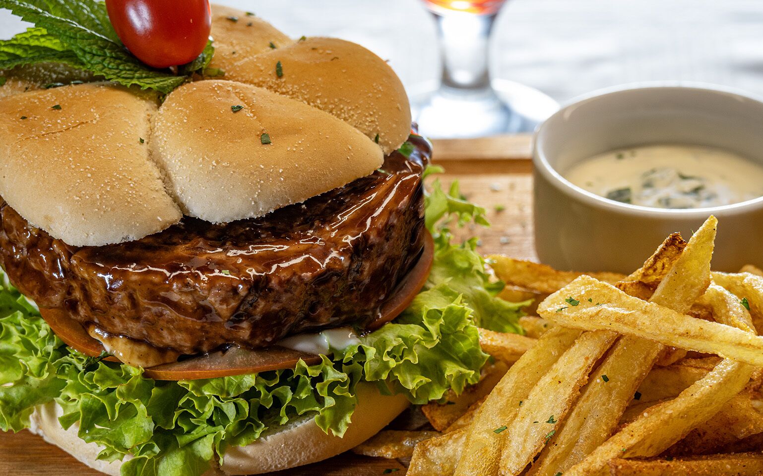 Una hamburguesa con lechuga, tomate y una porción de papas fritas.