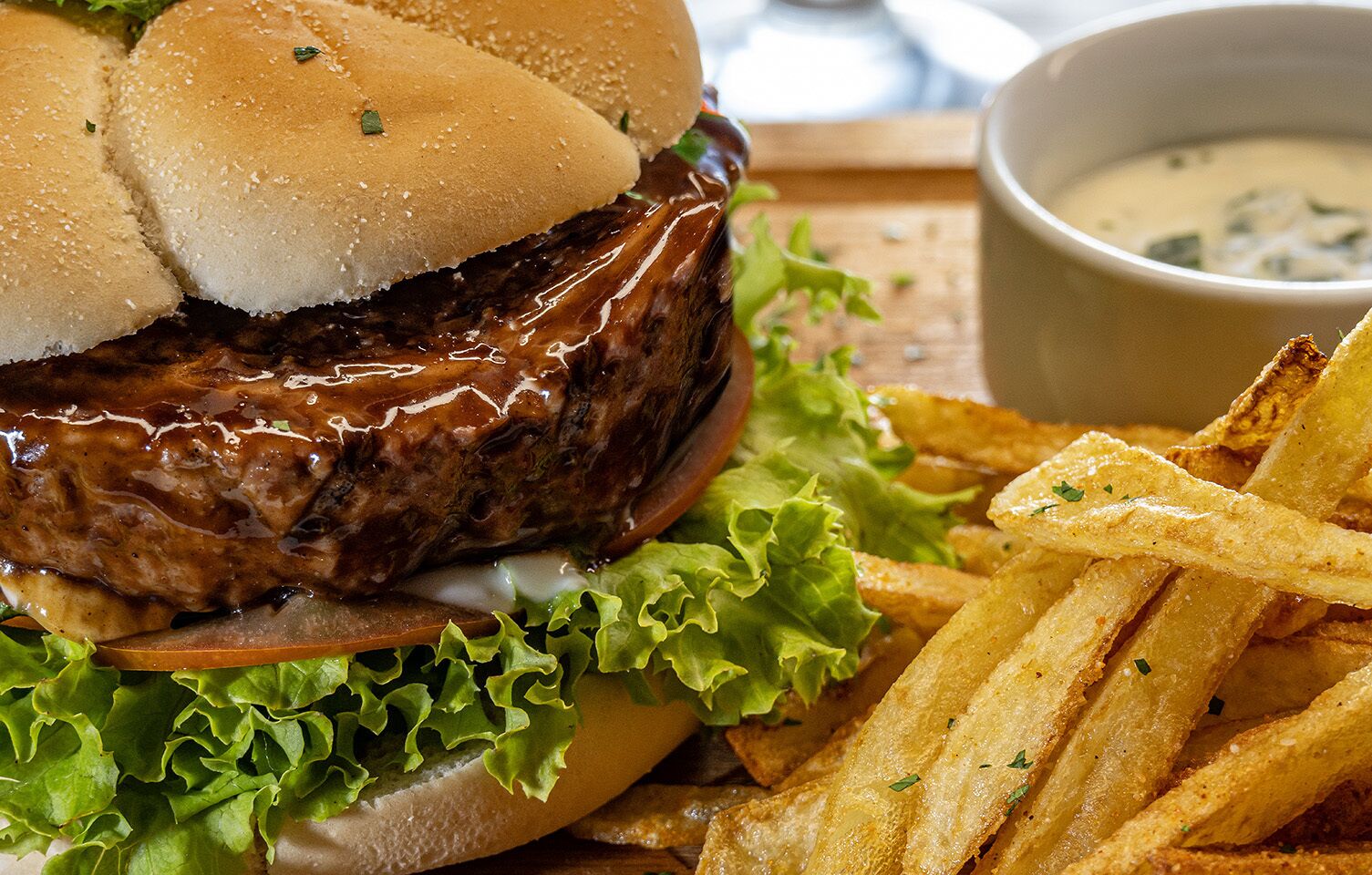 En hamburgare med pommes frites och en liten skål med sås.