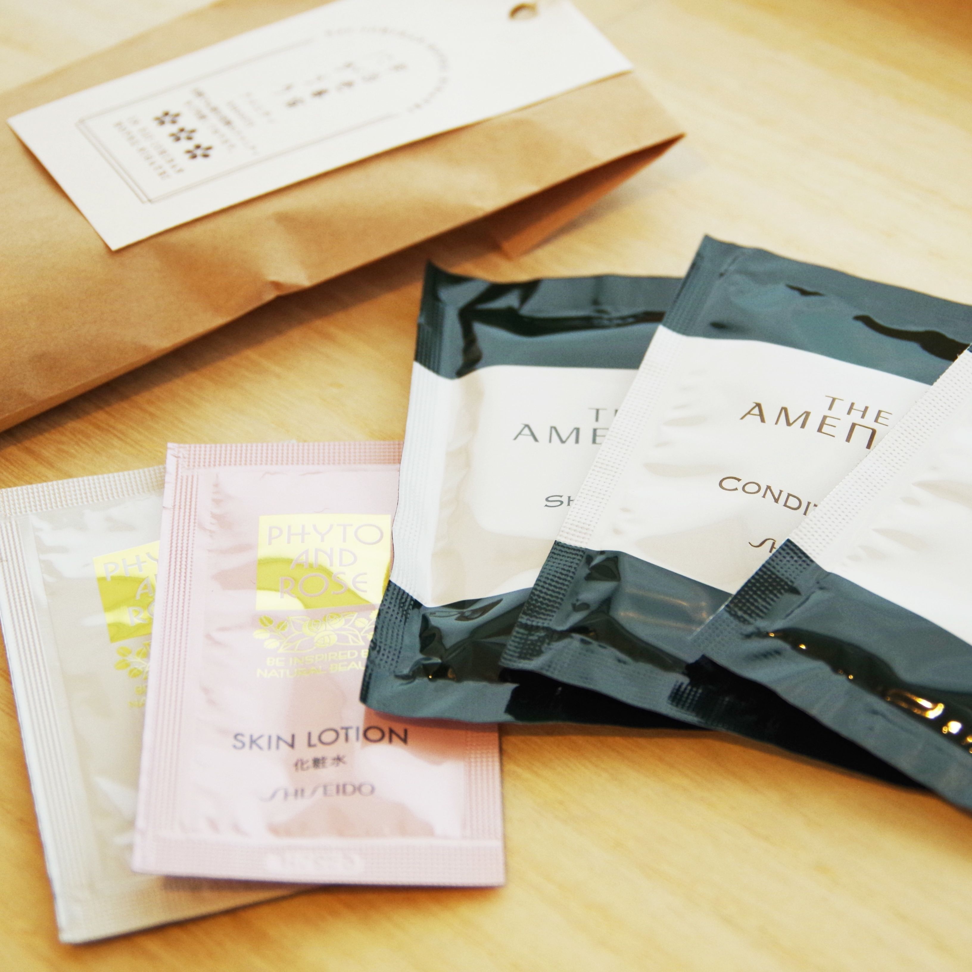 Superficie de madera con varios productos para el cuidado de la piel y una bolsa de papel marrón.