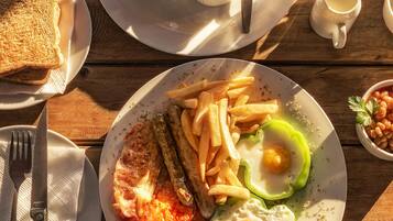 Een ontbijt bord met eieren, spek, tomaten en friet.