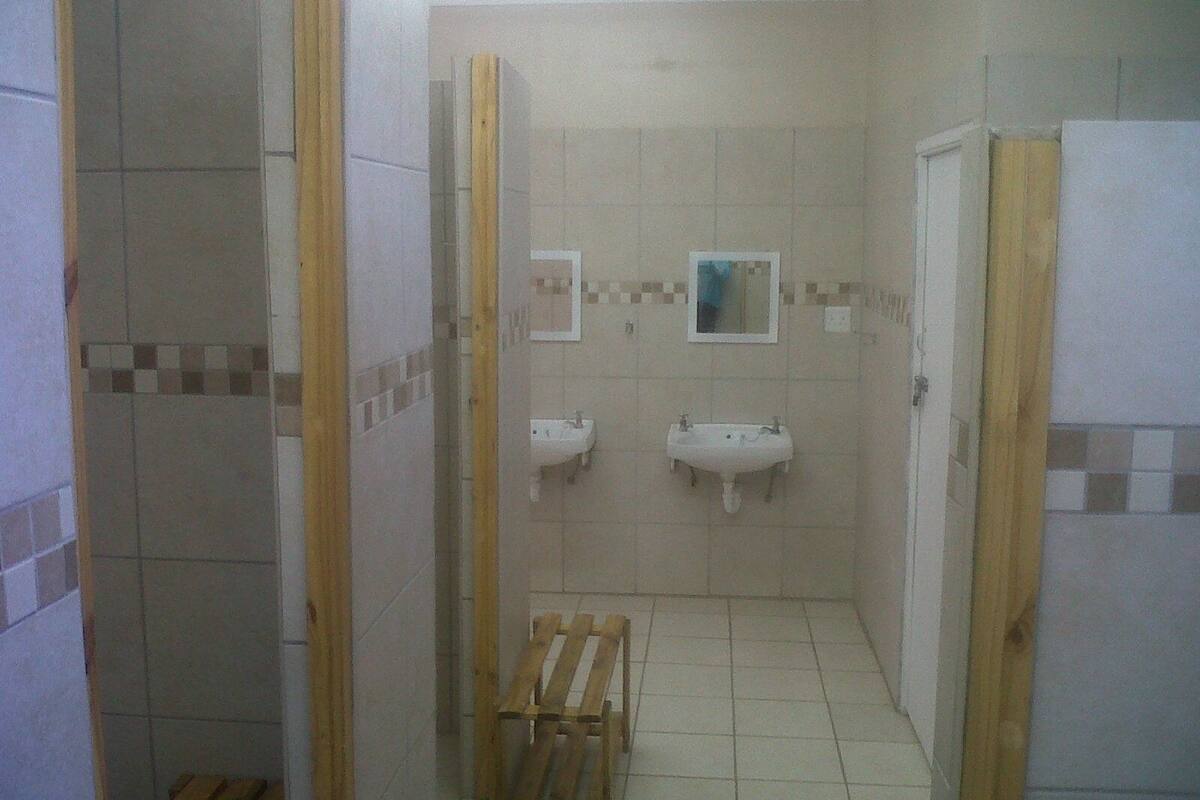 A bathroom with two sinks, a mirror, and a wooden bench.