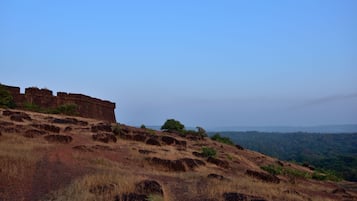 A dry, rocky landscape with a large, ancient stone structure on a hill.