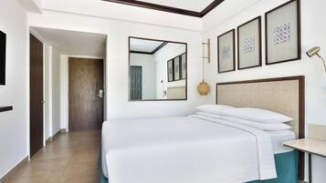 A hotel room with a large bed, a bedside table, a lamp, and framed artwork on the wall.