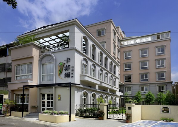 Un edificio de varios pisos con un logotipo y señalización destacados, balcones y una entrada portonada.