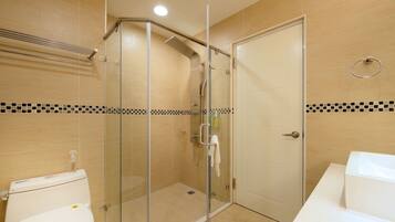 Une salle de bain avec une douche à parois de verre, des toilettes et un lavabo.