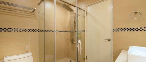A bathroom with a glass-enclosed shower, a toilet, and a sink.