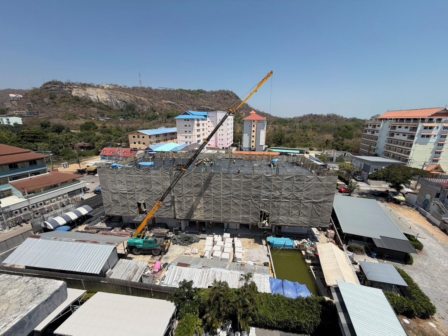 Eine Baustelle mit einem Kran, Gebäuden und einem großen, offenen Bereich voller Baumaterialien.