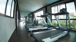 Un gimnasio con cintas de correr, bicicletas estáticas y máquinas de pesas.