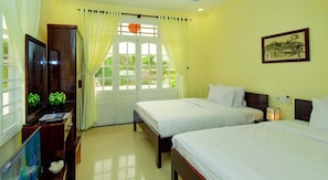 A hotel room with two beds, a TV, a desk with a computer, and a window with curtains. - Minh Phat Homestay (Da Nang)