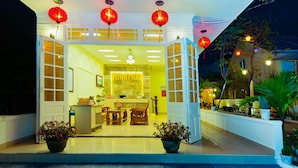 A brightly lit hotel entrance with a reception desk, chairs, and potted plants. - Minh Phat Homestay (Da Nang)