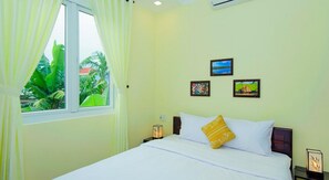 A bedroom with a bed, a window with curtains, and three framed pictures on the wall.