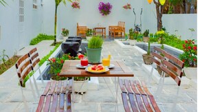 A patio with a table set for two, surrounded by potted plants and outdoor furniture. - Minh Phat Homestay (Da Nang)