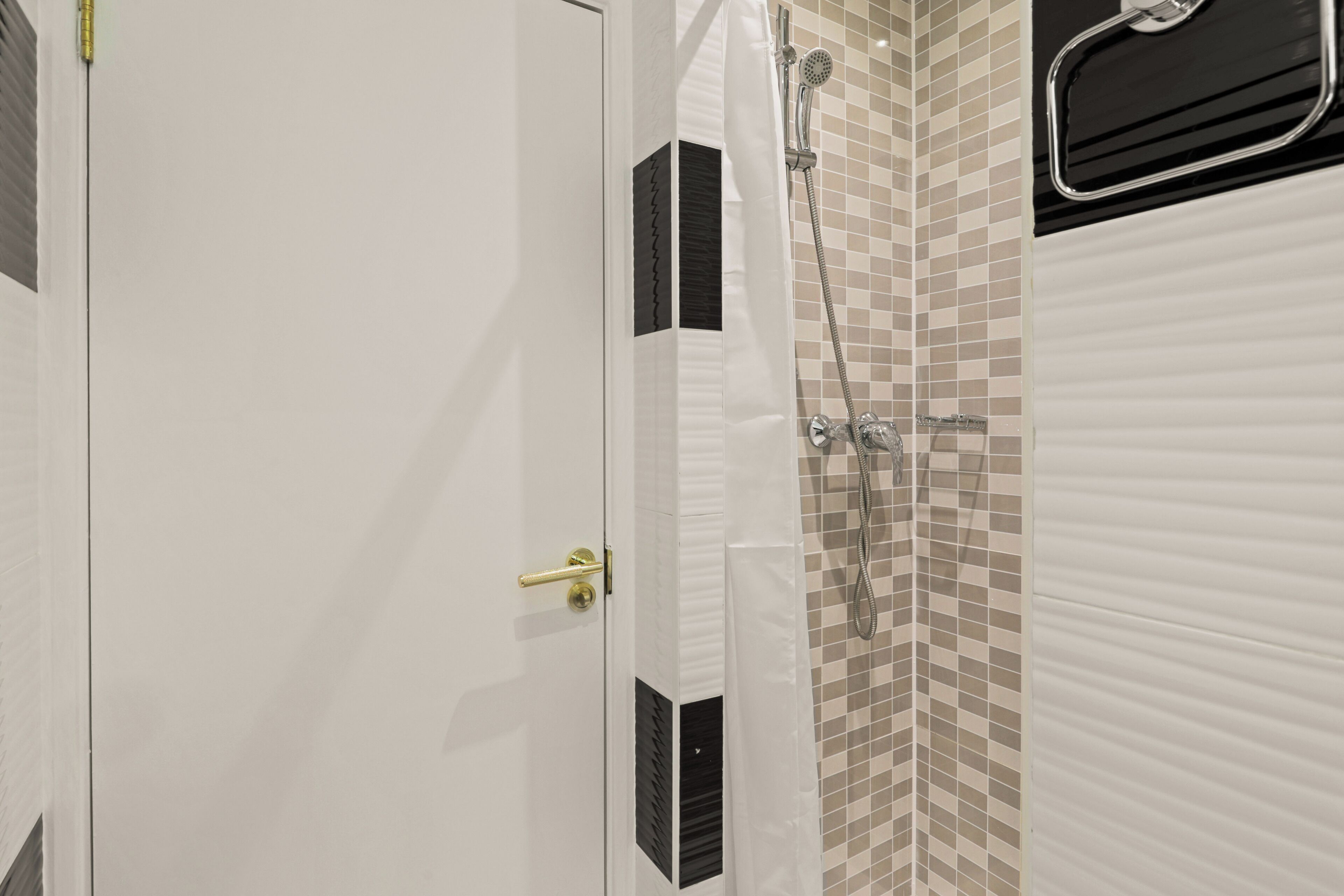Un baño con ducha, un perchero y una puerta con manija.