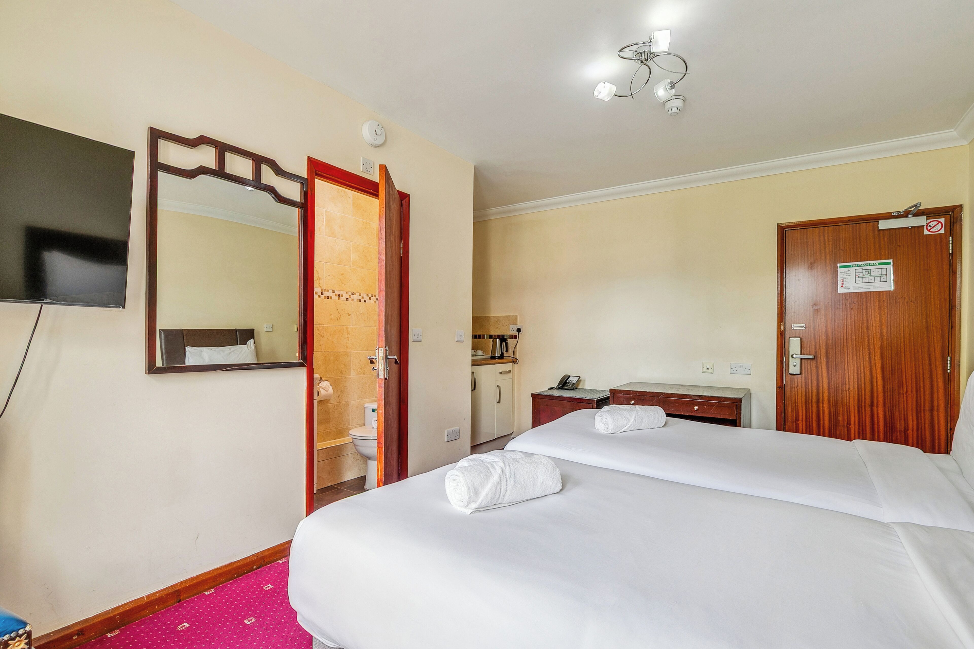 Una habitación de hotel con cama, televisión, baño y escritorio con teléfono.