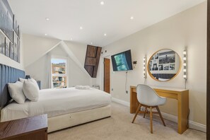 Une chambre à coucher avec un lit, un bureau avec une chaise, une télévision et un miroir avec éclairage intégré.