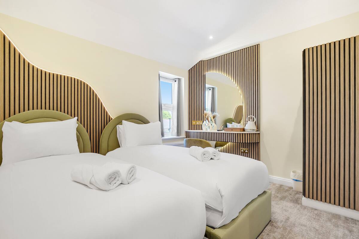 A hotel room with two beds, a large mirror, and a view of the outdoors.