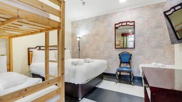 Habitación de hotel con literas, una cama individual, un escritorio, una silla y un espejo en la pared.