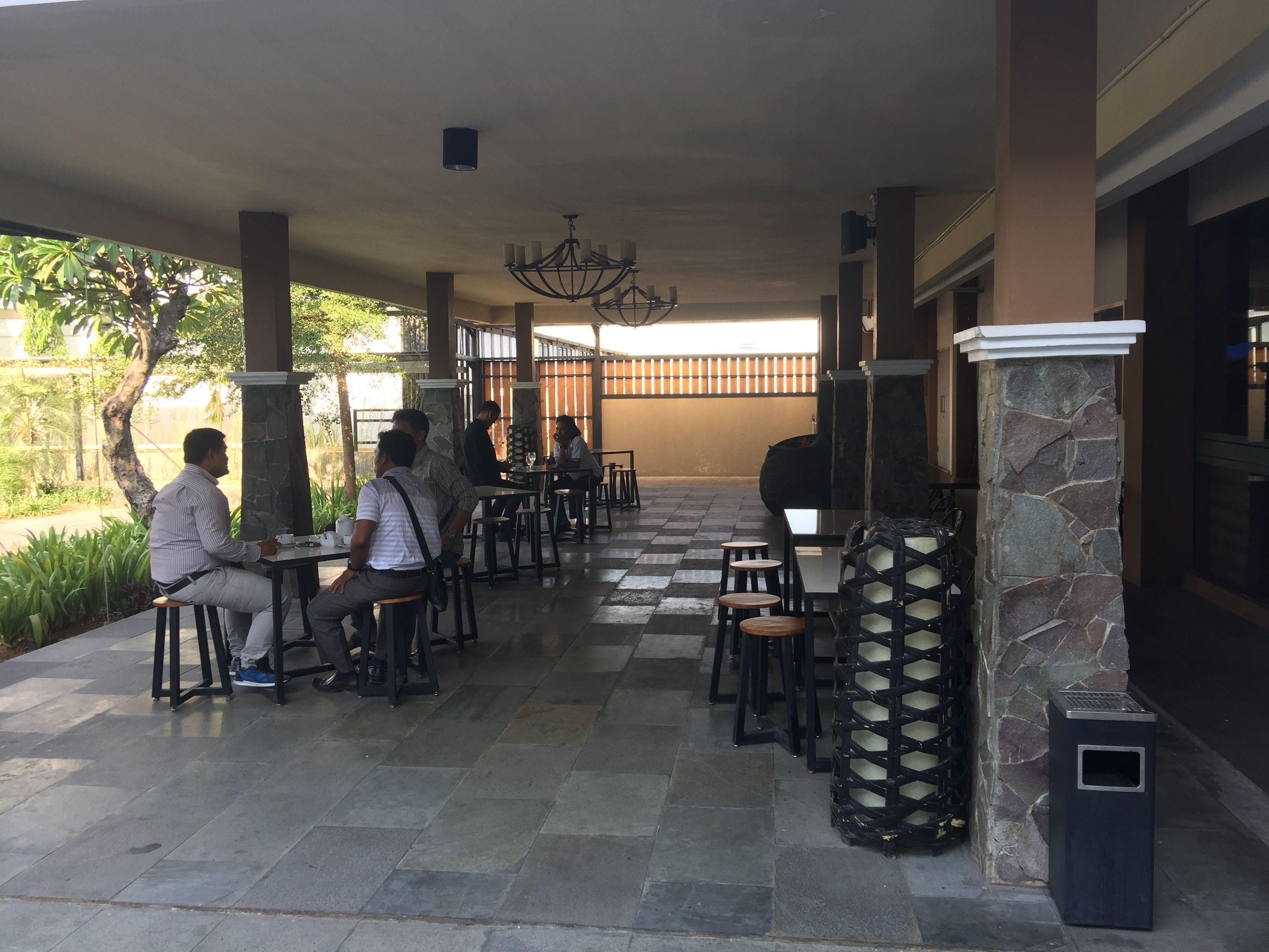 Un espace extérieur abrité, doté de piliers en pierre, de tables et de chaises.