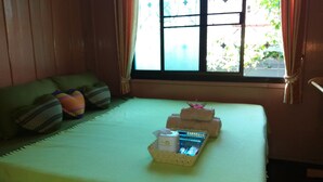 Une chambre avec un lit, des oreillers, une fenêtre et un panier contenant des articles de toilette.