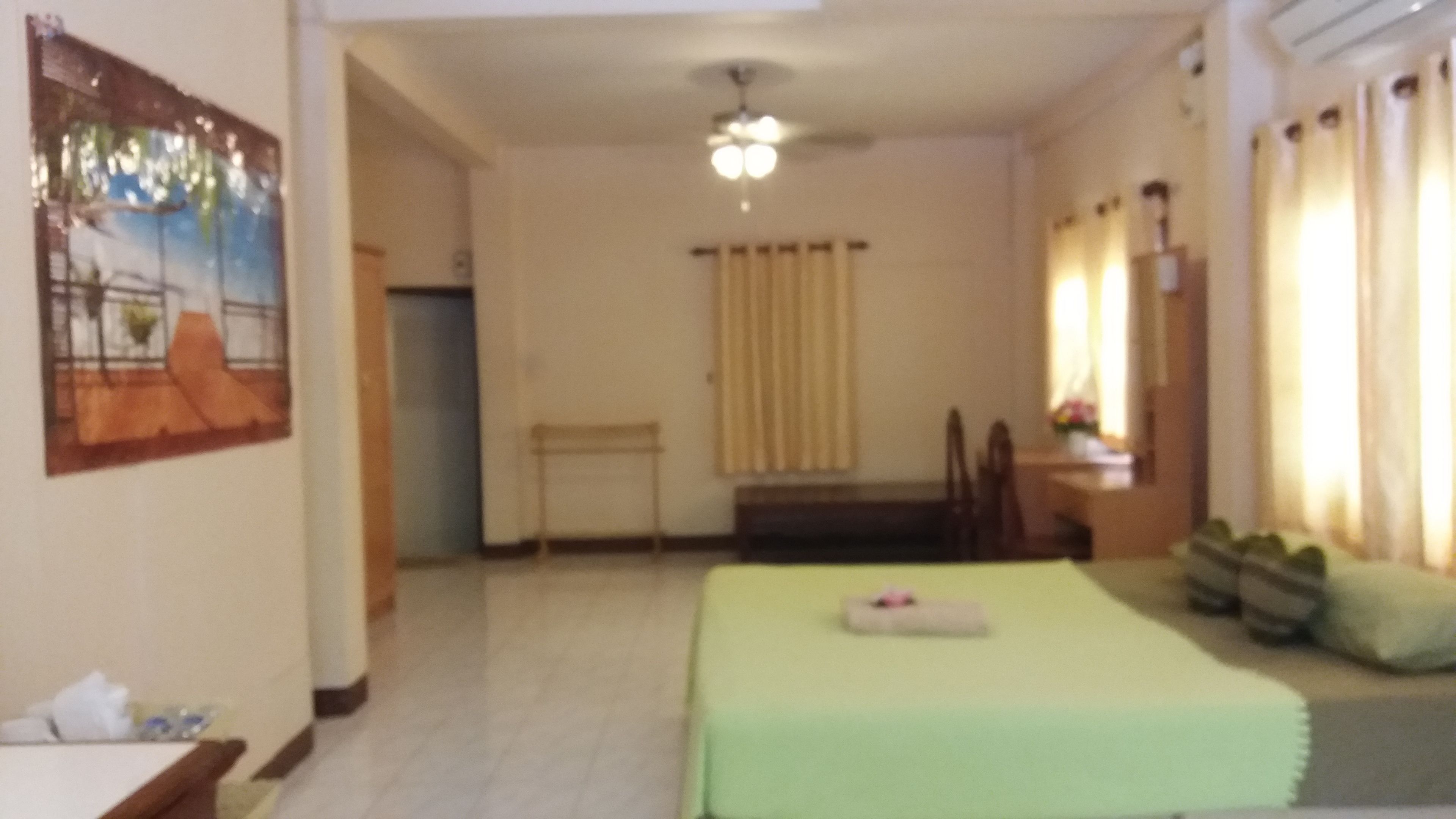 Habitación de hotel con cama, escritorio, silla, ventana con cortinas y un cuadro en la pared.