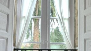 A table with tea set and a vase of flowers by a window with curtains. - La Casona Azul (Corvera de Toranzo)