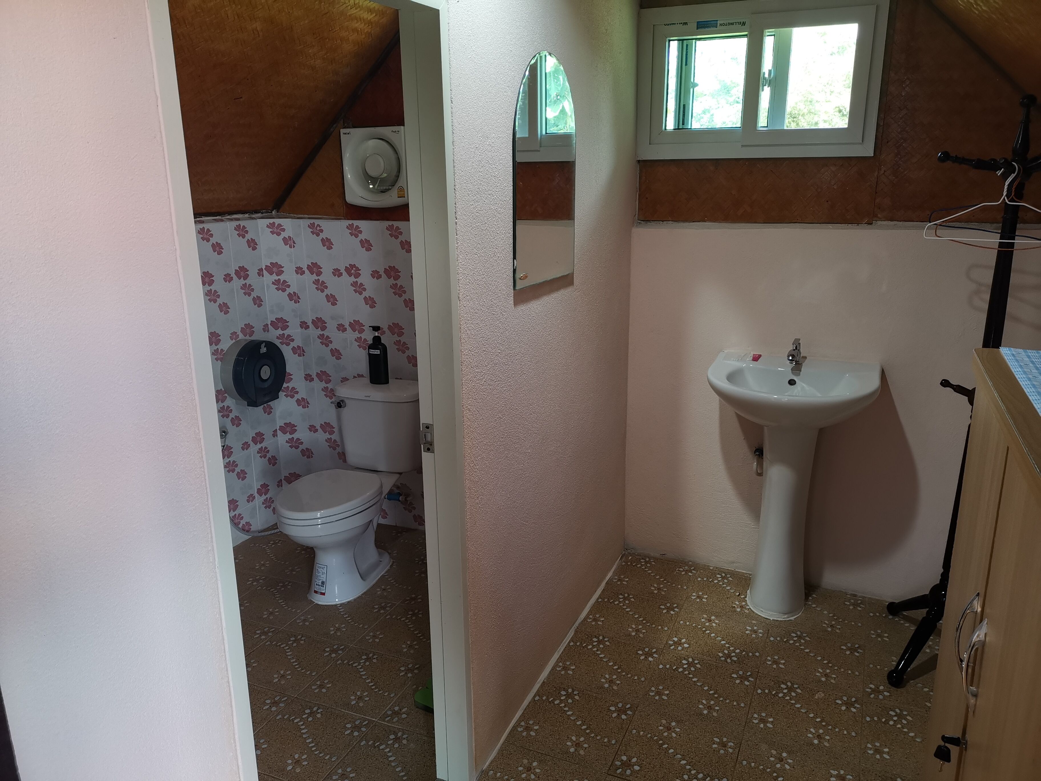 Un baño pequeño y funcional con inodoro, lavamanos y zona de ducha.
