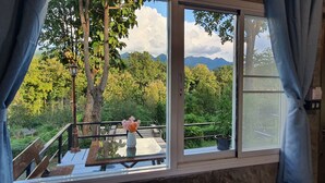 A room with a large window offering a view of a lush forest and mountains. - Banphu Montalang Resort (Mae Hong Son)