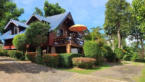 A two-story wooden house with a blue roof, surrounded by well-maintained gardens and trees. - Banphu Montalang Resort (Mae Hong Son)