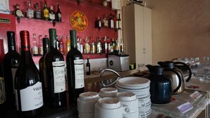 Zona de bar con varias botellas de licores, incluyendo vino y destilados, y una barra con platos, vasos y cubiertos.