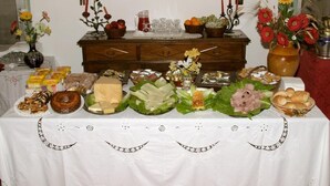 Una mesa dispuesta con diversos alimentos y elementos decorativos, incluyendo un florero con flores y un candelabro.