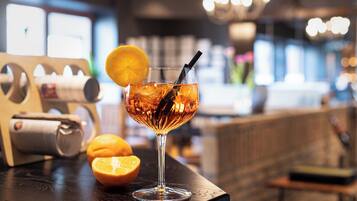 Een cocktailglas met een citroenpartje en een rietje op een houten bartafel.