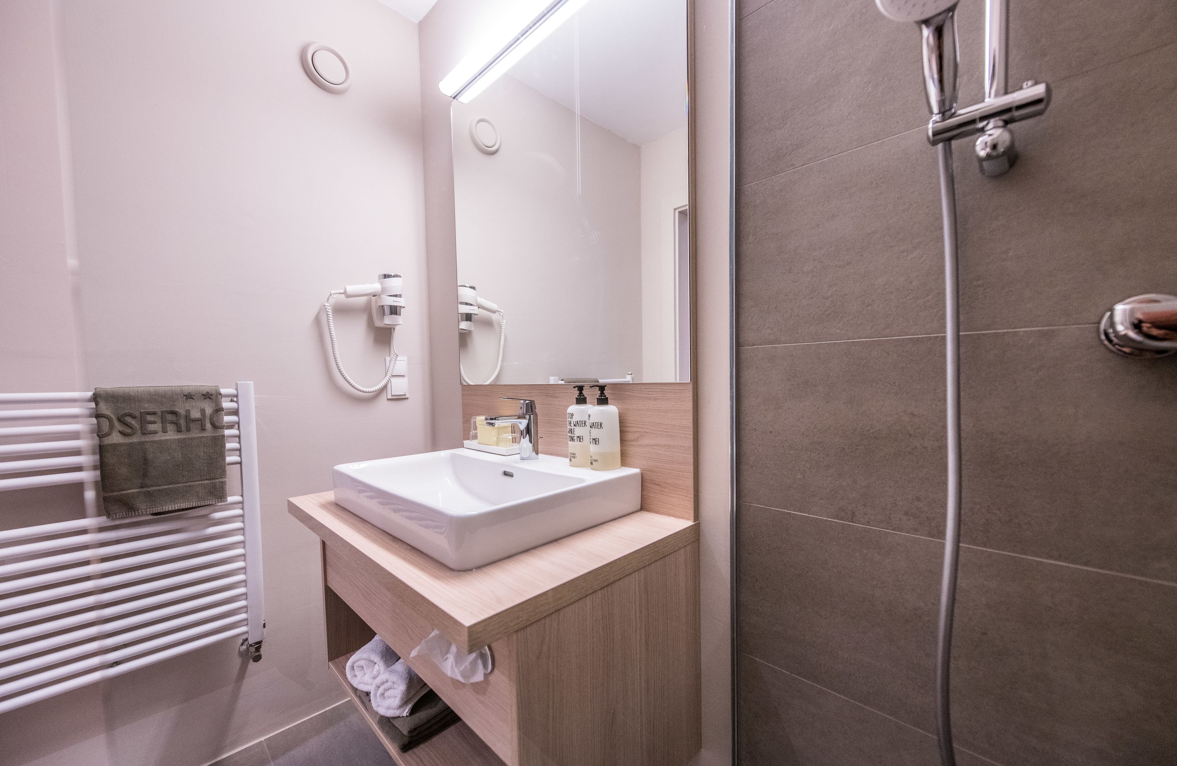 A modern bathroom with a white sink, mirror, and shower.