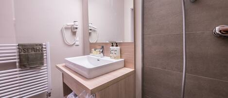 A modern bathroom with a white sink, mirror, and shower.
