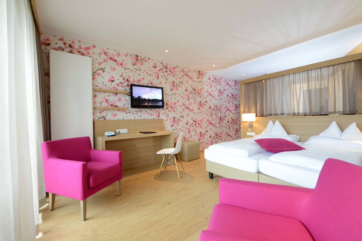 Una habitación de hotel con cama, escritorio, silla y televisor.