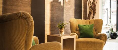 A modern living room with a large window, a sofa, a chair, and a small table with a plant.