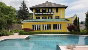 A yellow building with a swimming pool in front. - Kaiser Franz Josef (Millstatt)