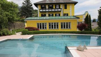 Un bâtiment jaune avec une piscine devant.