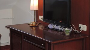 A wooden desk with a flat-screen TV, a lamp, and a small vase with flowers. - Kaiser Franz Josef (Millstatt)