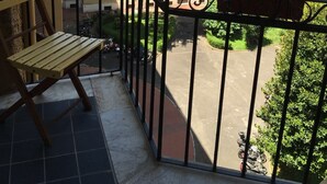A balcony with a wooden bench, potted plants, and a view of a multi-story building with balconies. - Relais Incantesimo Vaticano (Rome)