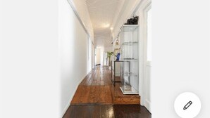A hallway with wooden flooring, white walls, and a glass display cabinet. - Relais Incantesimo Vaticano (Rome)
