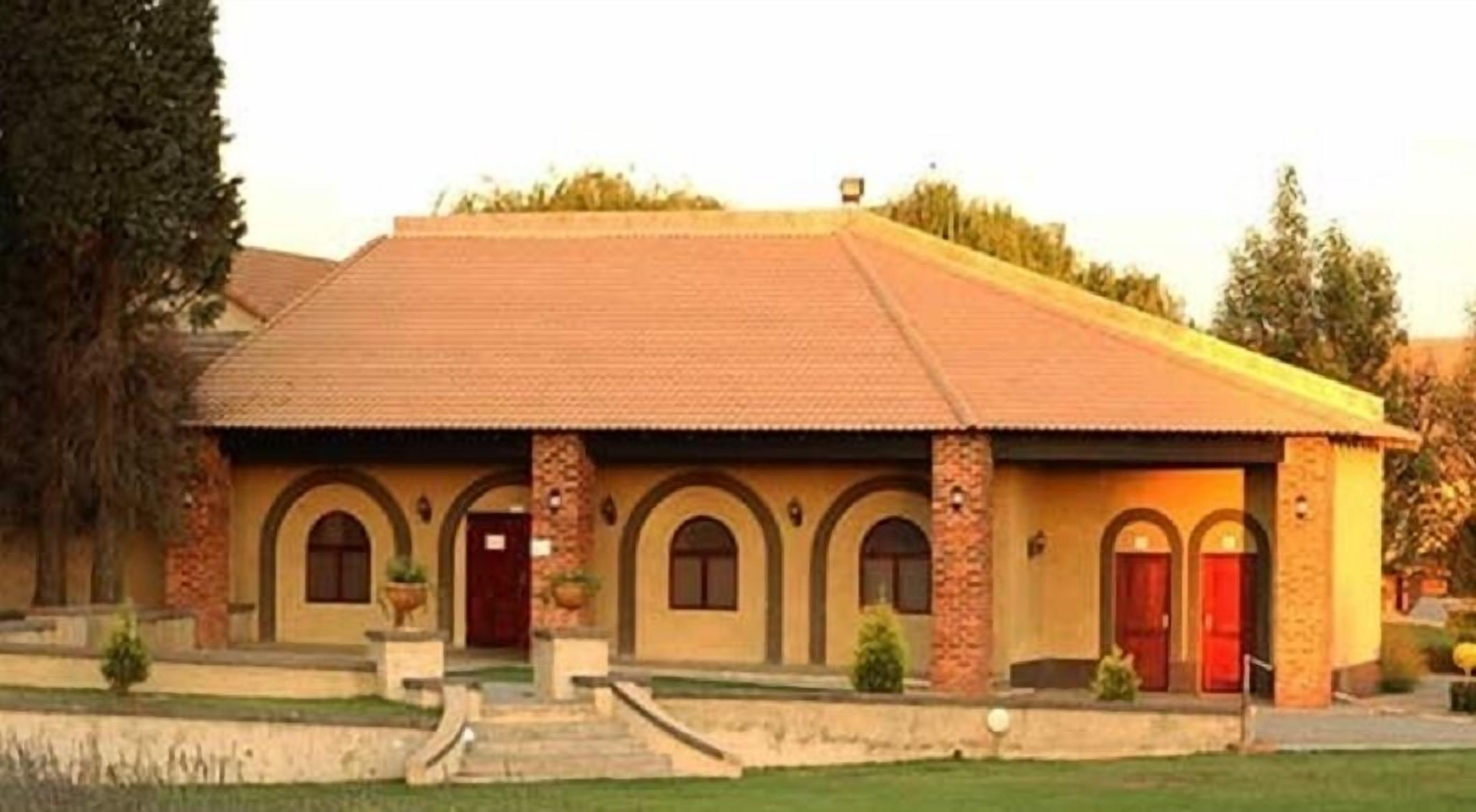 A building with a tiled roof, multiple arched doorways, and a small front garden.