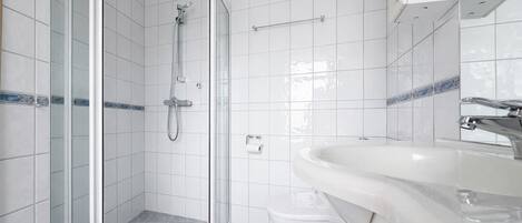 Une salle de bain avec une douche à parois de verre, des toilettes et un lavabo avec un miroir.