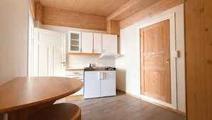 Eine Küche mit Holzausstattung, einem weißen Kühlschrank und einem Holzessttisch.