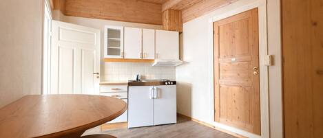 Une cuisine avec des meubles de rangement en bois, un réfrigérateur blanc et une table à manger en bois.