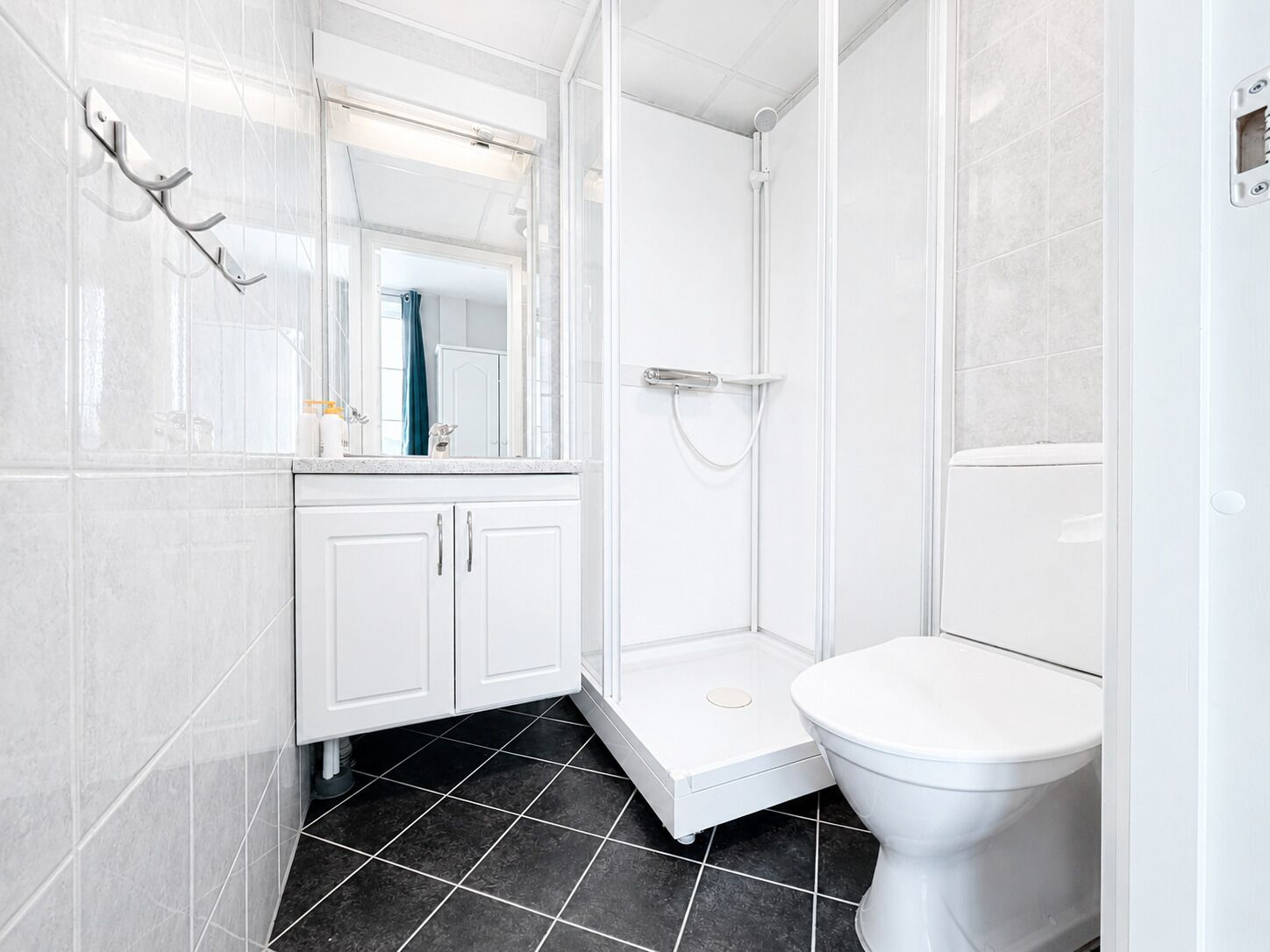 Un bagno moderno con il water bianco, un box doccia e un mobile lavabo con pensili.