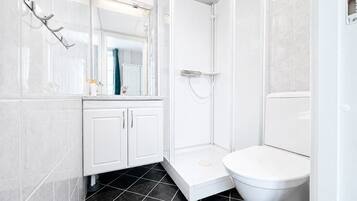 Un bagno moderno con il water bianco, un box doccia e un mobile lavabo con pensili.