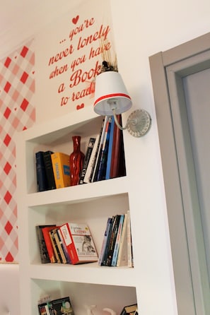 A bookshelf with books and a decorative wall with a quote. - I Love Piramide (Rome)